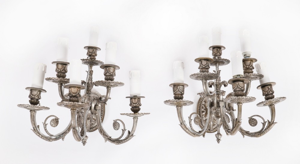 A set of four silver-plated six-branch wall sconces featuring scrolling arms, foliate details, and faux candle sleeves. View XIII