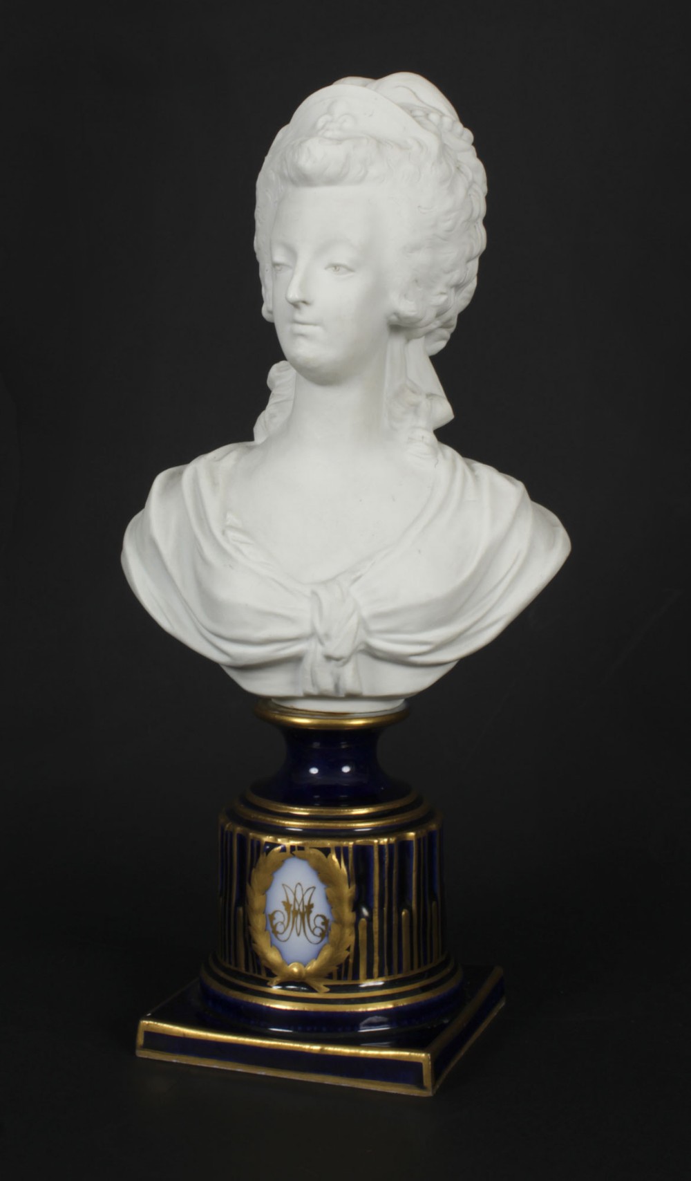 A 19th-century white bisque porcelain bust of Marie Antoinette on a cobalt blue and gilded glazed pedestal.