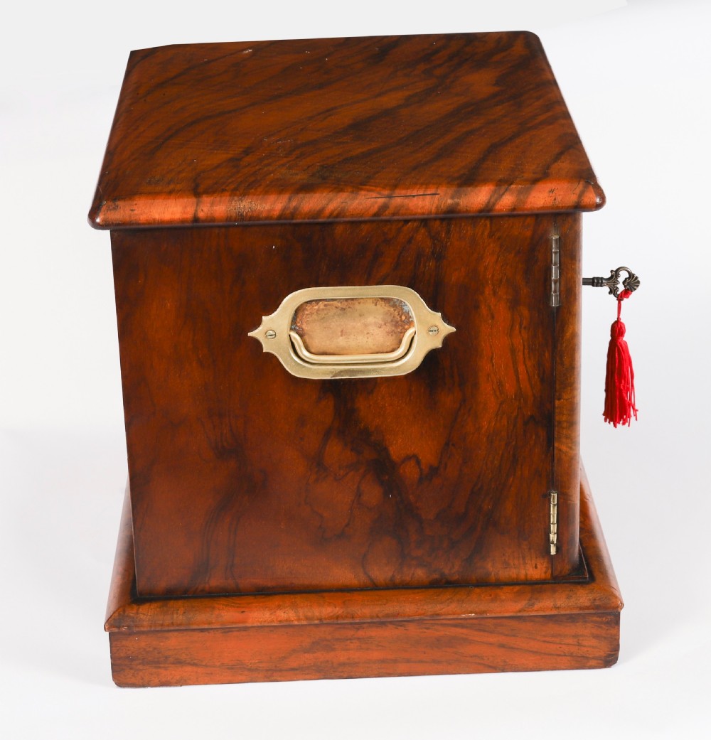 A Victorian burr walnut desktop cigar cabinet featuring brass campaign carry handles, twin doors, a moulded plinth base, and a key with a red tassel. View VI