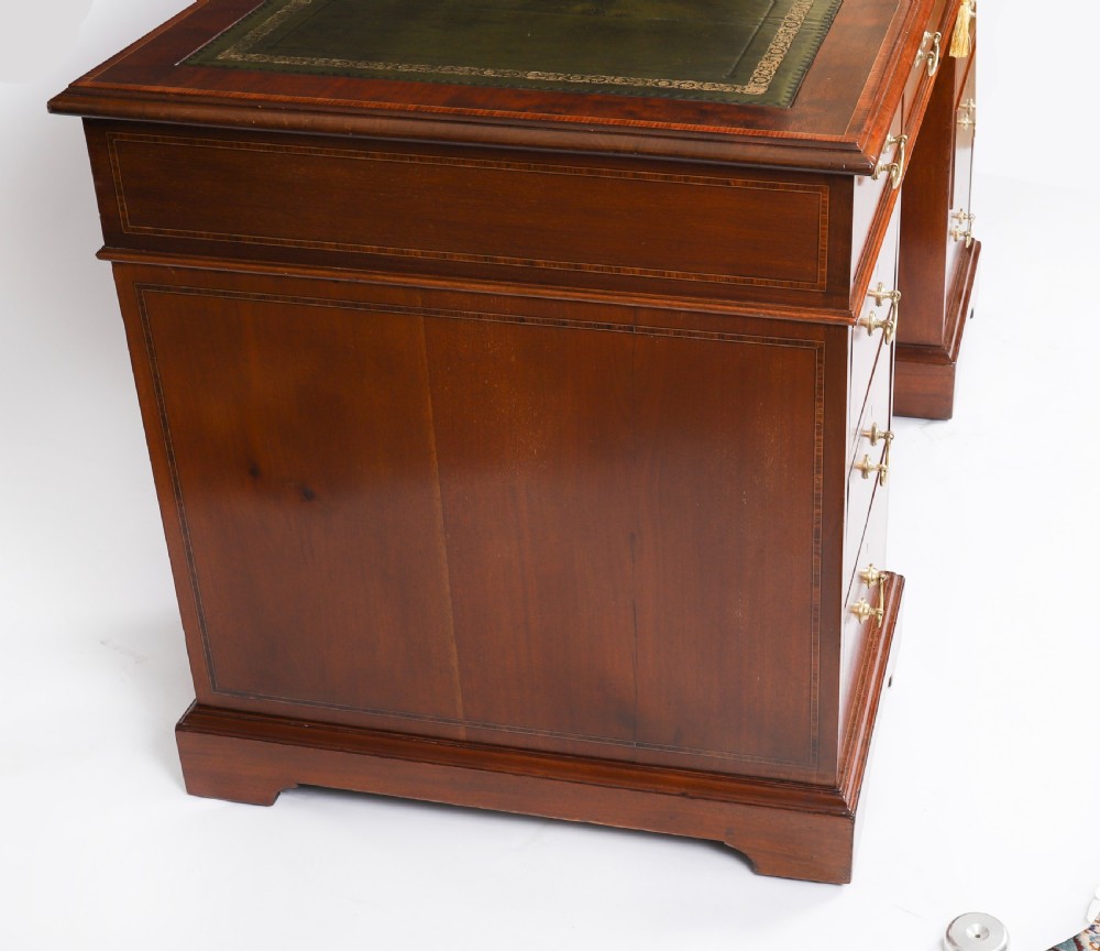 A Victorian flame mahogany pedestal desk featuring a green leather inset writing surface, crossbanded drawers with brass swan-neck handles, and plinth bases. View XIV