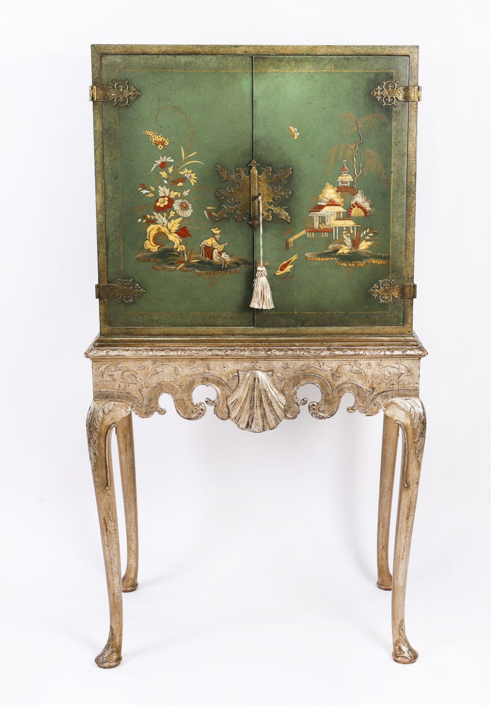 A green lacquered two-door cocktail cabinet with hand-painted chinoiserie scenes resting on a carved silver gilt stand with cabriole legs.