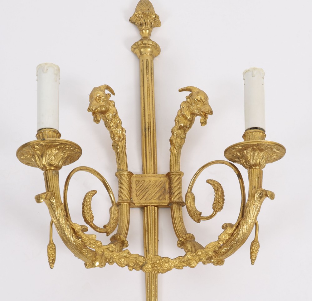 A pair of nineteenth-century French Neoclassical gilt bronze wall lights featuring twin candle arms decorated with goat heads and pinecone finials. View III
