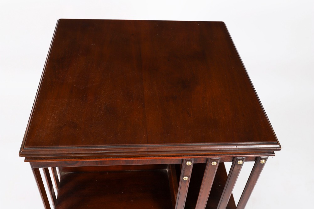 A two-tier dark mahogany revolving bookcase featuring vertical slatted sides with brass stud detailing, resting on a quadform base with castors. View III