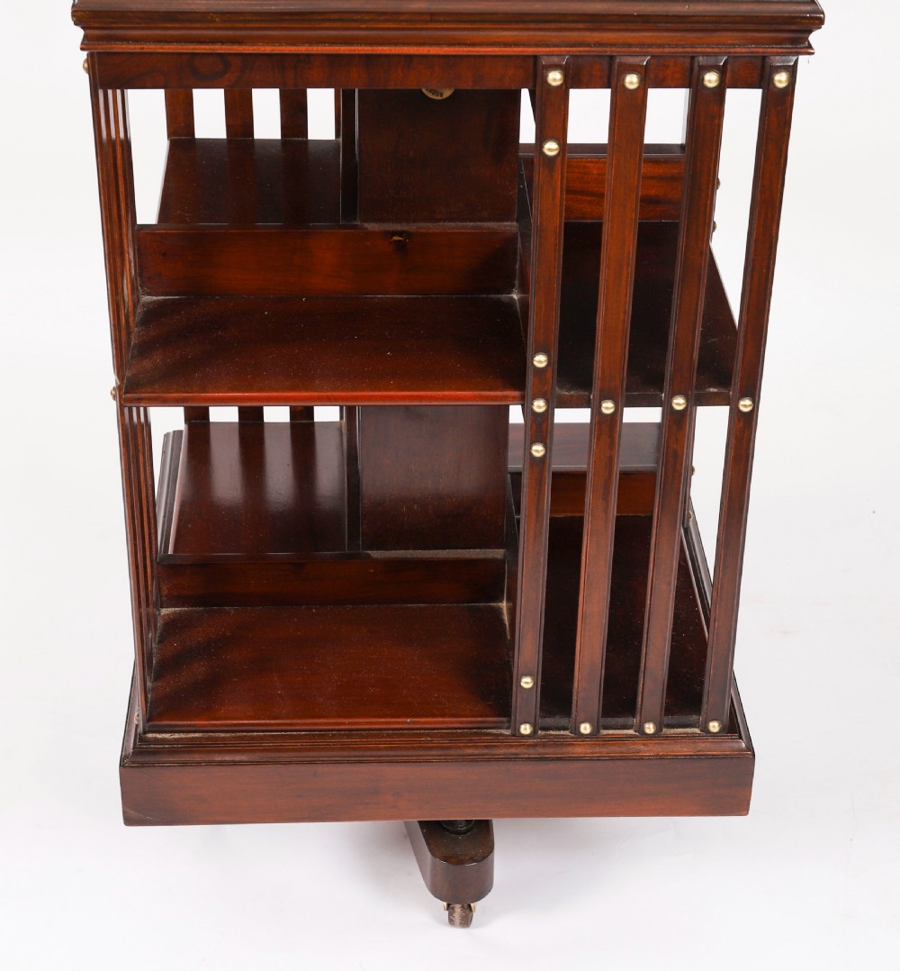 A two-tier dark mahogany revolving bookcase featuring vertical slatted sides with brass stud detailing, resting on a quadform base with castors. View VI