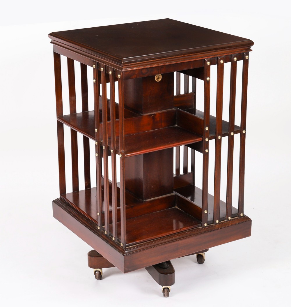 A two-tier dark mahogany revolving bookcase featuring vertical slatted sides with brass stud detailing, resting on a quadform base with castors. View XI
