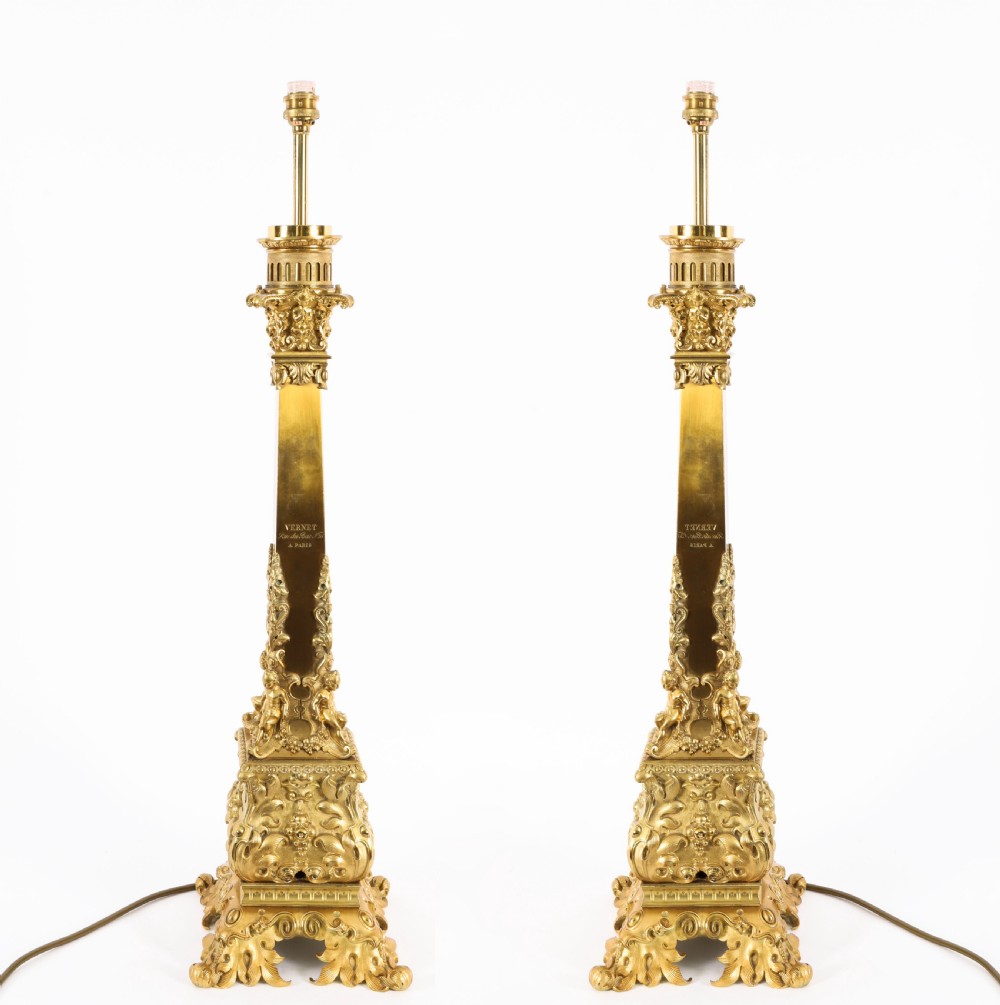 A pair of 19th-century French ormolu table lamps featuring cast gilt bronze bases and cream flared fabric shades with tassel fringe trim. View II