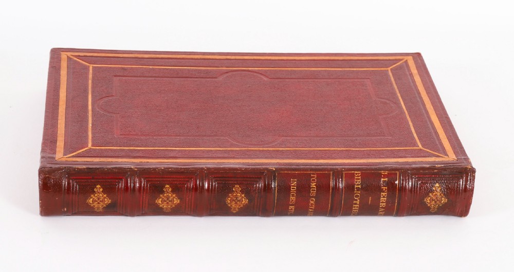 An open red marbled book-form box displaying seven oval cream plaster intaglios behind glass alongside an engraved frontispiece. View VI