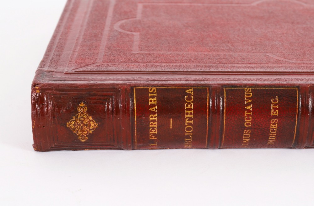 An open red marbled book-form box displaying seven oval cream plaster intaglios behind glass alongside an engraved frontispiece. View X