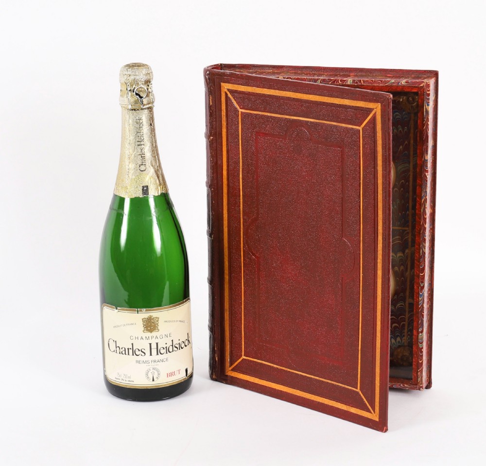 An open red marbled book-form box displaying seven oval cream plaster intaglios behind glass alongside an engraved frontispiece. View XIX