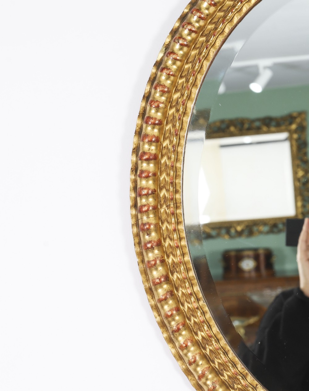 A matching pair of 19th-century French oval wall mirrors featuring carved giltwood frames with a beaded pattern and gold leaf finish. View VI