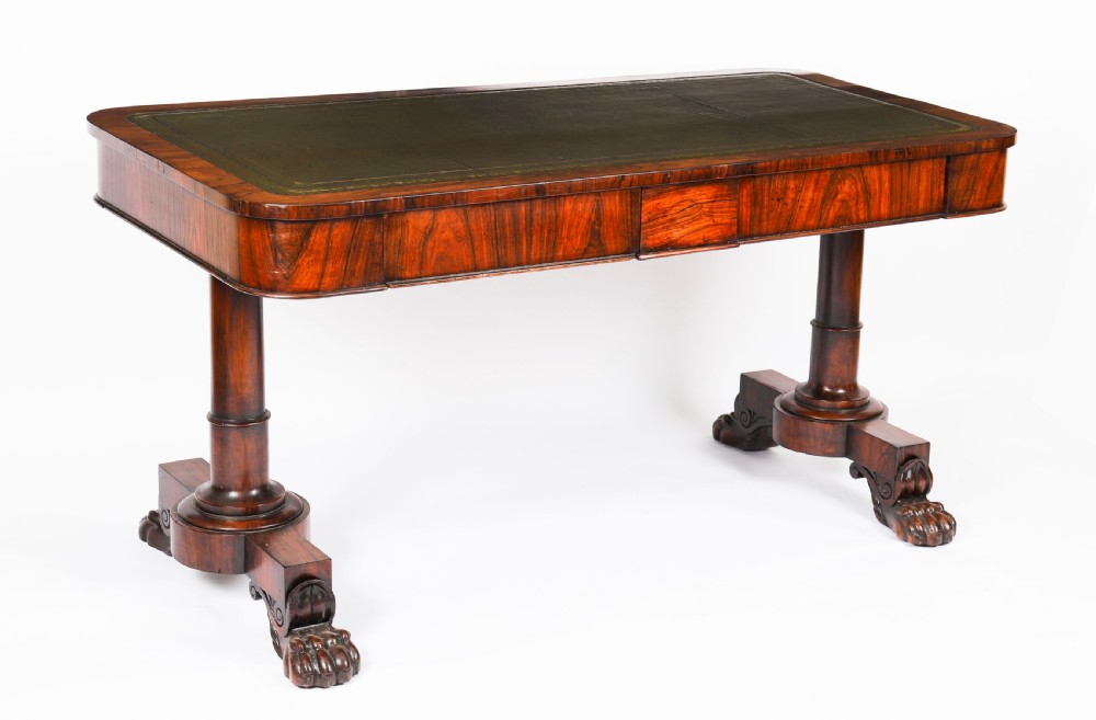 A nineteenth-century William IV writing table crafted from Goncalo Alves wood featuring a green leather top and carved paw feet.