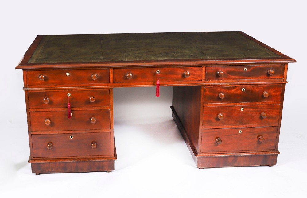 A Victorian flame mahogany partners pedestal desk featuring a green leather inset writing surface and turned wooden knobs. View II