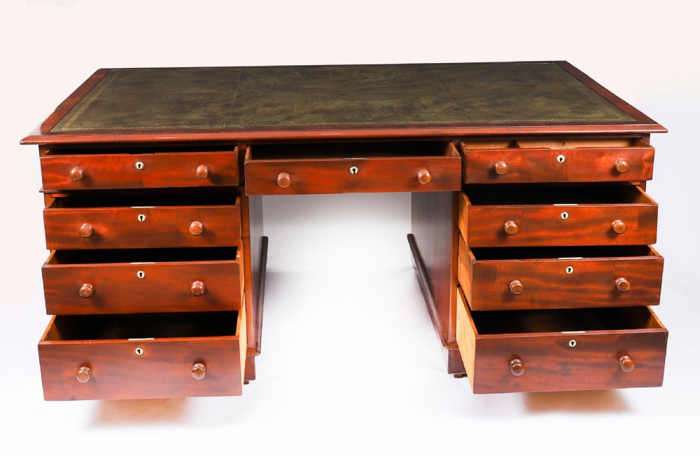 A Victorian flame mahogany partners pedestal desk featuring a green leather inset writing surface and turned wooden knobs. View III