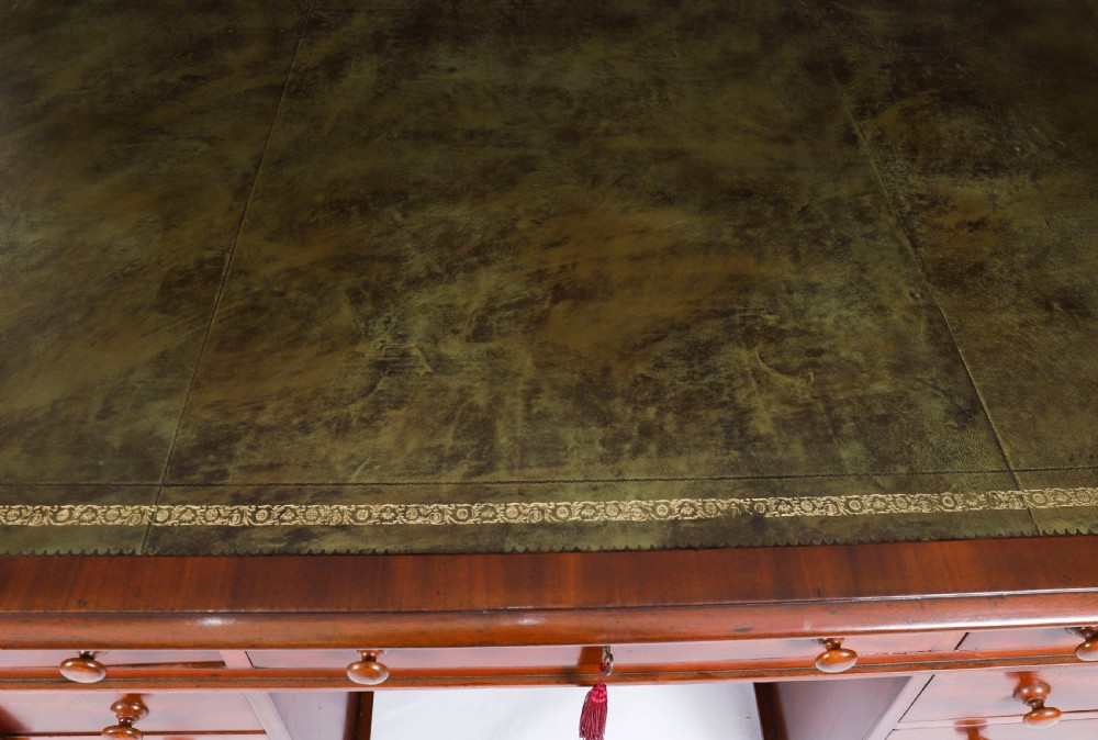 A Victorian flame mahogany partners pedestal desk featuring a green leather inset writing surface and turned wooden knobs. View IV
