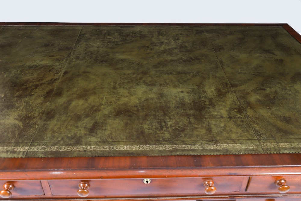 A Victorian flame mahogany partners pedestal desk featuring a green leather inset writing surface and turned wooden knobs. View V