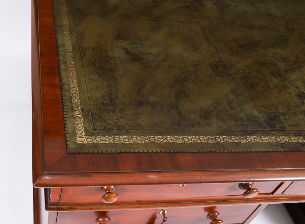A Victorian flame mahogany partners pedestal desk featuring a green leather inset writing surface and turned wooden knobs. View VI
