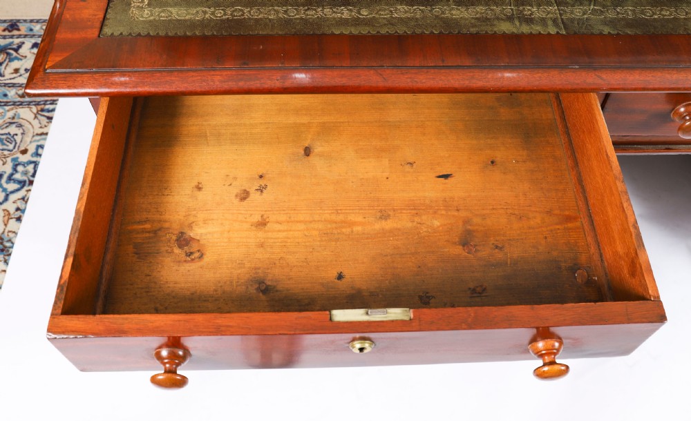 A Victorian flame mahogany partners pedestal desk featuring a green leather inset writing surface and turned wooden knobs. View VIII