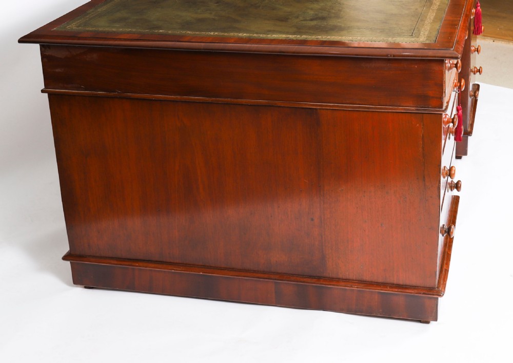 A Victorian flame mahogany partners pedestal desk featuring a green leather inset writing surface and turned wooden knobs. View XI