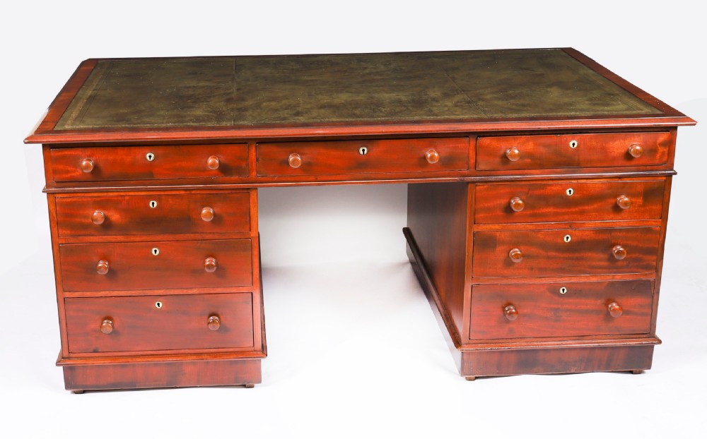 A Victorian flame mahogany partners pedestal desk featuring a green leather inset writing surface and turned wooden knobs. View XII