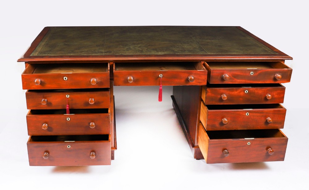 A Victorian flame mahogany partners pedestal desk featuring a green leather inset writing surface and turned wooden knobs. View XIII