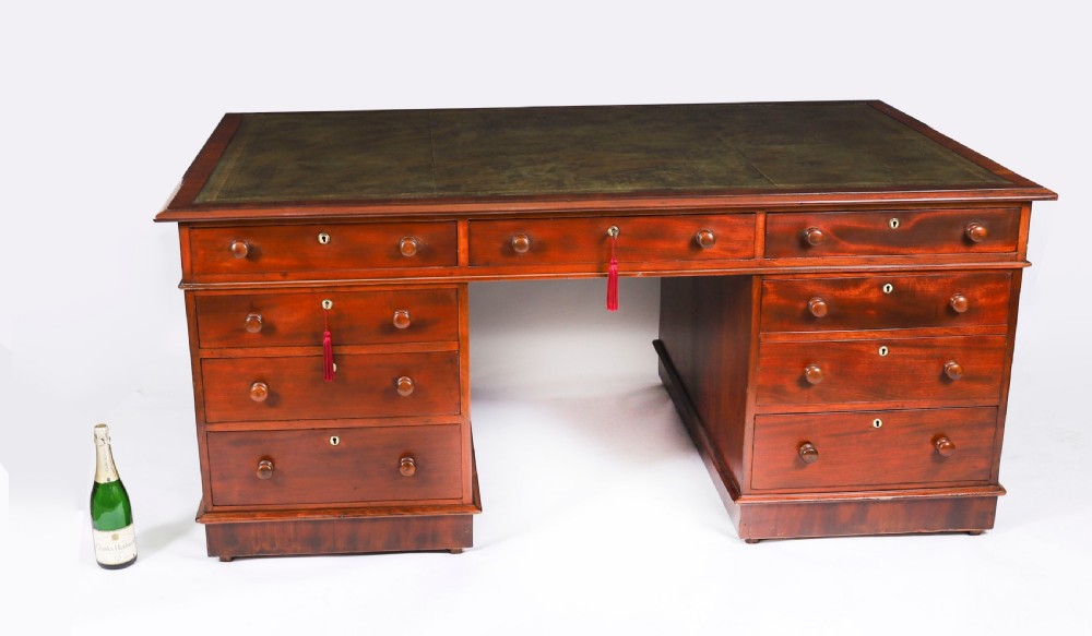 A Victorian flame mahogany partners pedestal desk featuring a green leather inset writing surface and turned wooden knobs. View XIX