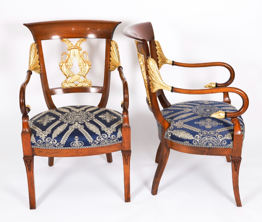 A pair of Italian Neoclassical armchairs featuring dark wood frames with giltwood swan carved back splats and blue patterned upholstered seats. View XVI