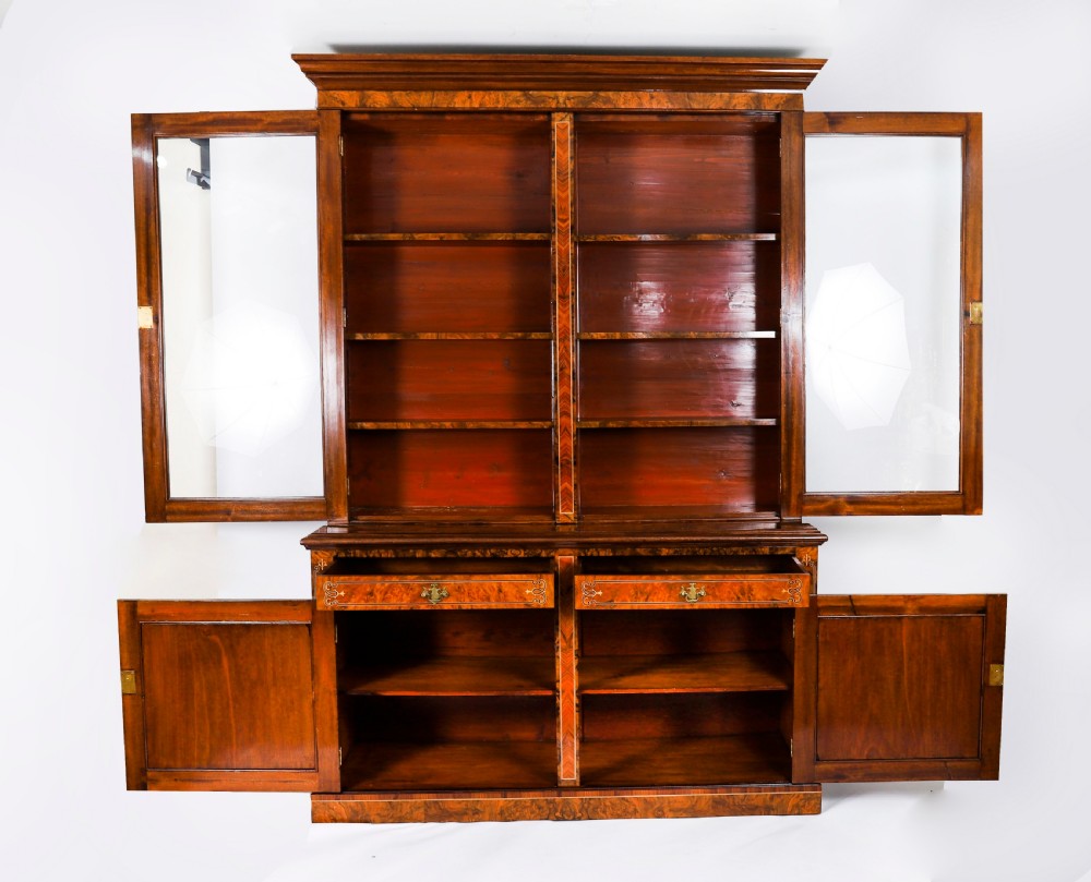 A 19th-century Victorian burr walnut bookcase featuring upper glazed doors, intricate inlay detailing, two drawers, and lower cupboard doors. View IV
