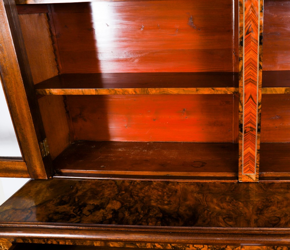 A 19th-century Victorian burr walnut bookcase featuring upper glazed doors, intricate inlay detailing, two drawers, and lower cupboard doors. View IX