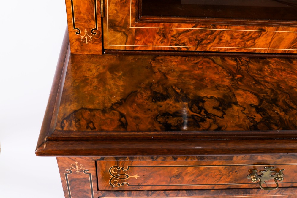 A 19th-century Victorian burr walnut bookcase featuring upper glazed doors, intricate inlay detailing, two drawers, and lower cupboard doors. View XIII