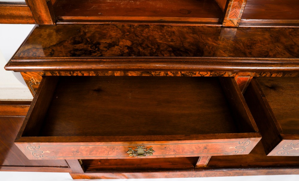 A 19th-century Victorian burr walnut bookcase featuring upper glazed doors, intricate inlay detailing, two drawers, and lower cupboard doors. View XVI