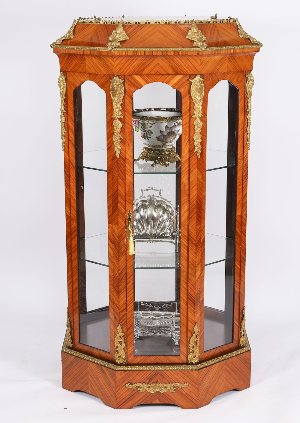 An octagonal kingwood display cabinet featuring chevron parquetry veneers, gilt bronze mounts, and glazed panels housing internal glass shelves. View II