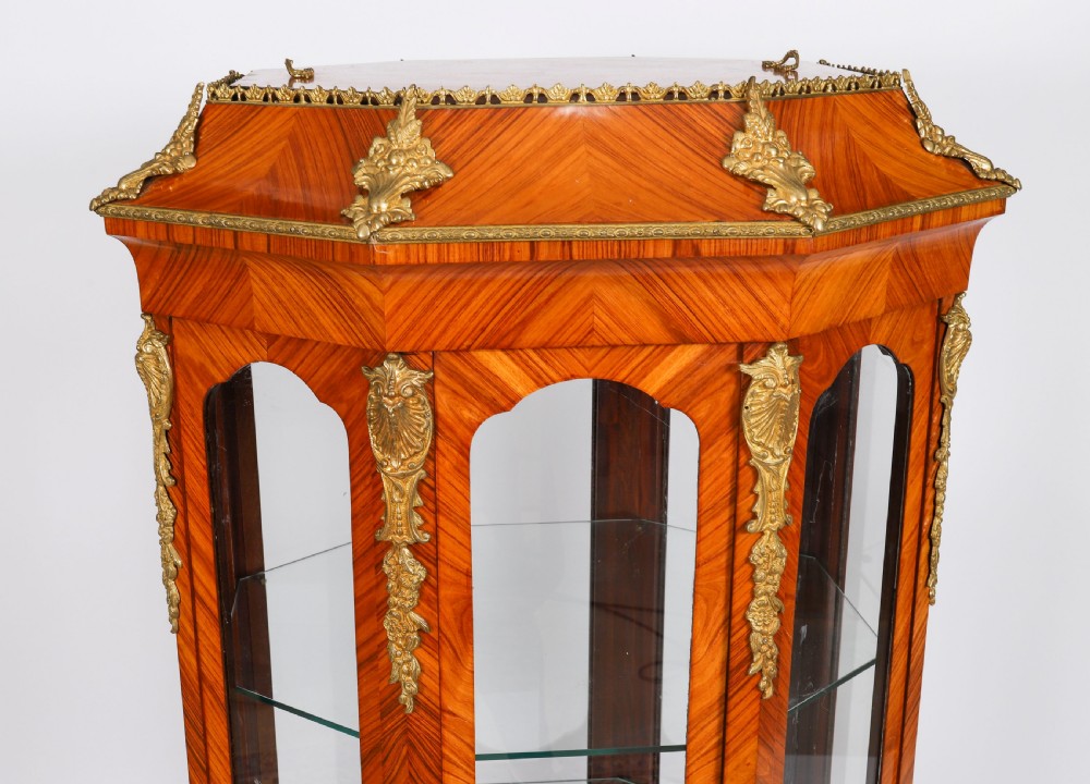 An octagonal kingwood display cabinet featuring chevron parquetry veneers, gilt bronze mounts, and glazed panels housing internal glass shelves. View III