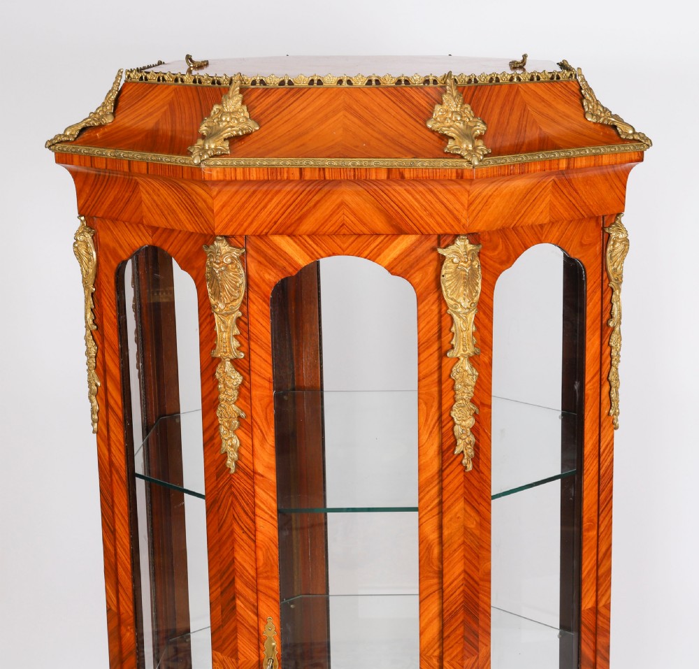 An octagonal kingwood display cabinet featuring chevron parquetry veneers, gilt bronze mounts, and glazed panels housing internal glass shelves. View XII