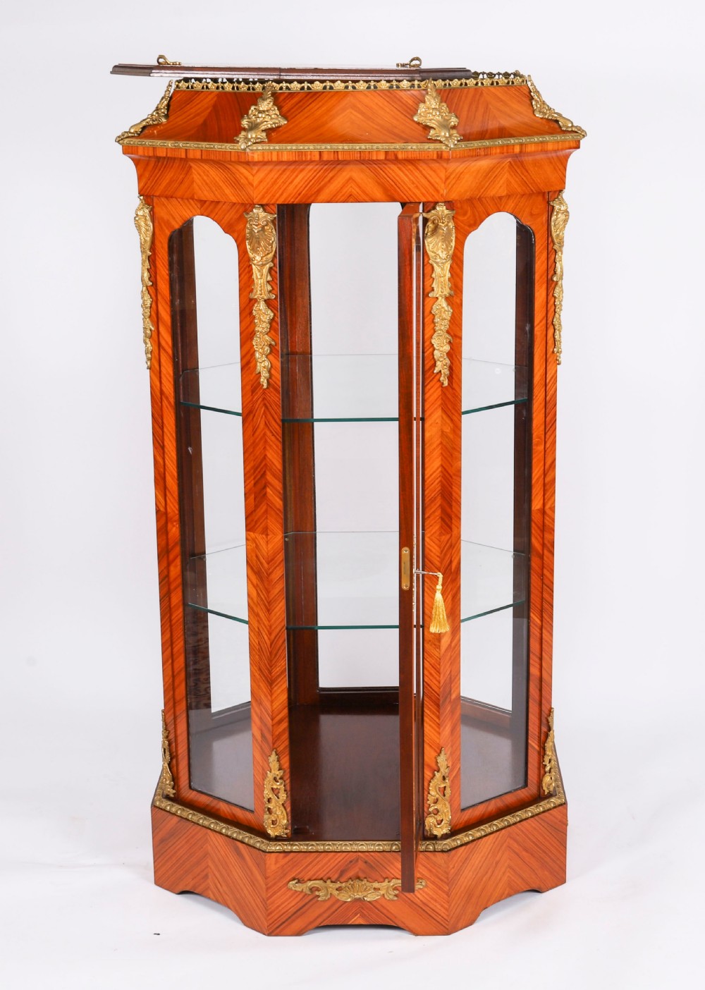 An octagonal kingwood display cabinet featuring chevron parquetry veneers, gilt bronze mounts, and glazed panels housing internal glass shelves. View XIV