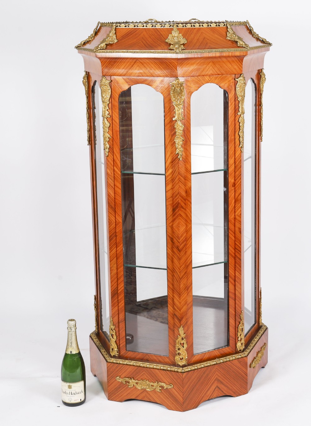 An octagonal kingwood display cabinet featuring chevron parquetry veneers, gilt bronze mounts, and glazed panels housing internal glass shelves. View XV