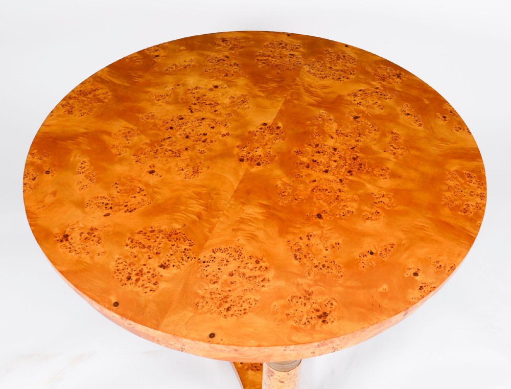 A circular 20th-century Biedermeier revival coffee table made from burr elm with three column legs set on a triform plinth base. View III