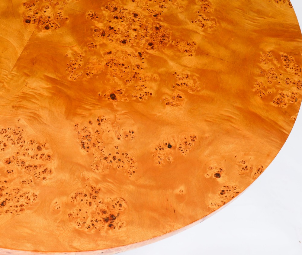 A circular 20th-century Biedermeier revival coffee table made from burr elm with three column legs set on a triform plinth base. View VI
