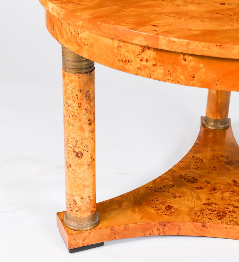 A circular 20th-century Biedermeier revival coffee table made from burr elm with three column legs set on a triform plinth base. View VIII