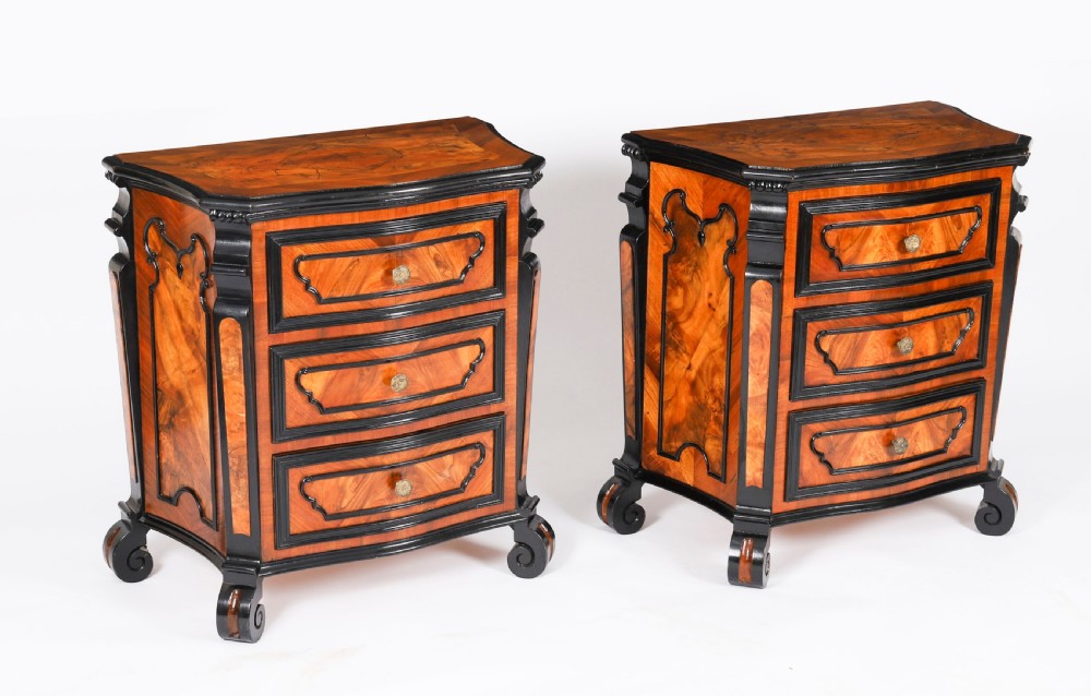 A pair of 18th-century Italian burr walnut serpentine bedside chests featuring ebonised mouldings, three drawers, and scroll feet.