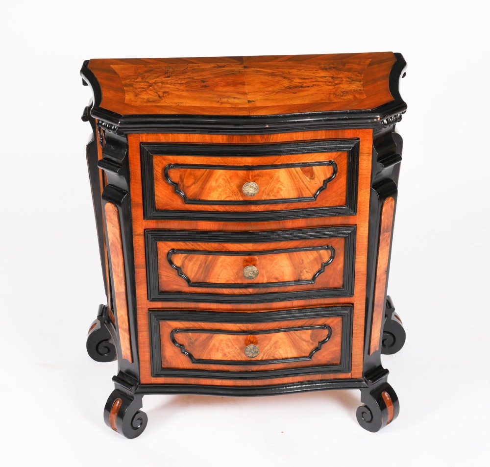 A pair of 18th-century Italian burr walnut serpentine bedside chests featuring ebonised mouldings, three drawers, and scroll feet. View VII