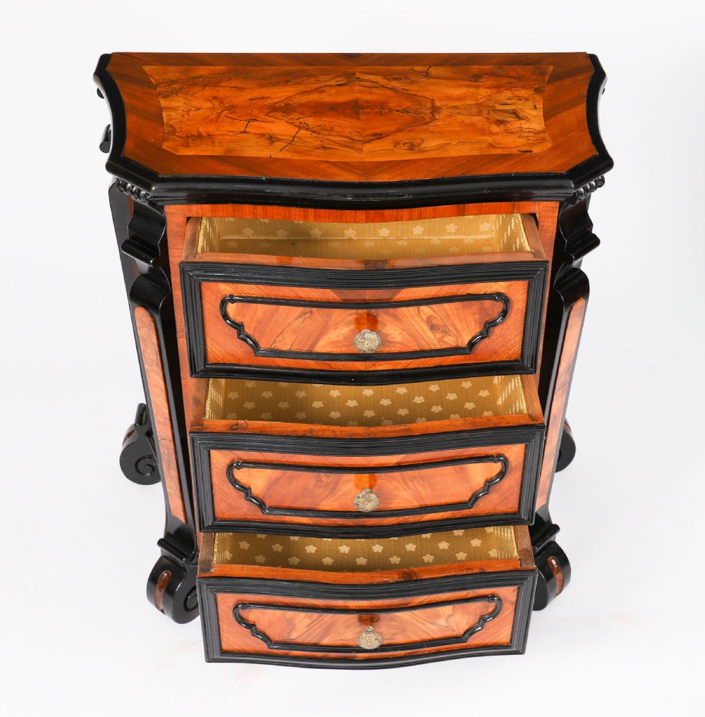 A pair of 18th-century Italian burr walnut serpentine bedside chests featuring ebonised mouldings, three drawers, and scroll feet. View XII