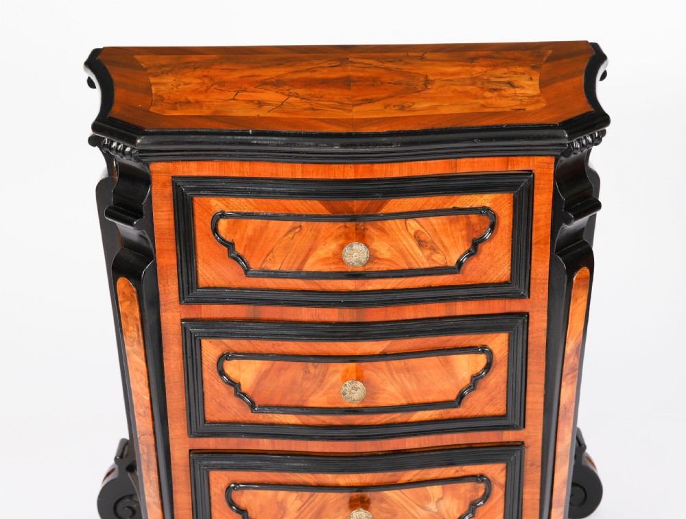 A pair of 18th-century Italian burr walnut serpentine bedside chests featuring ebonised mouldings, three drawers, and scroll feet. View XV