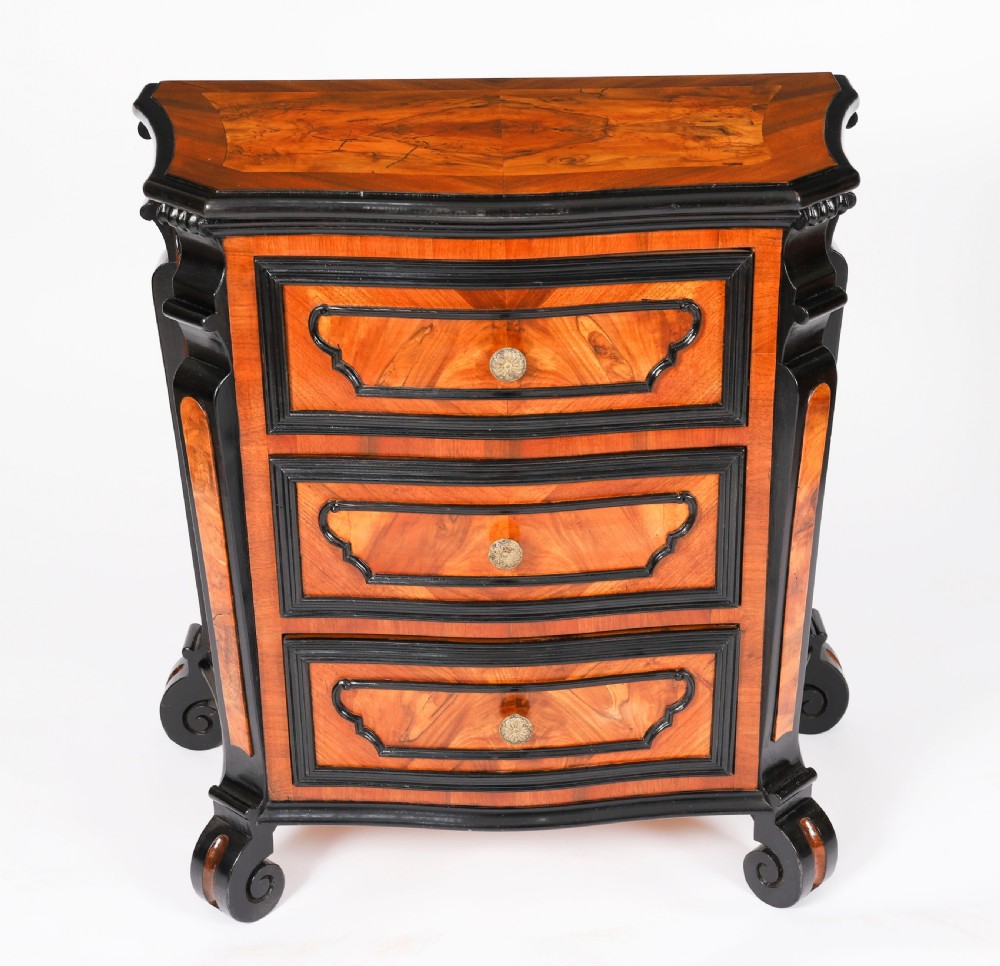 A pair of 18th-century Italian burr walnut serpentine bedside chests featuring ebonised mouldings, three drawers, and scroll feet. View XVI