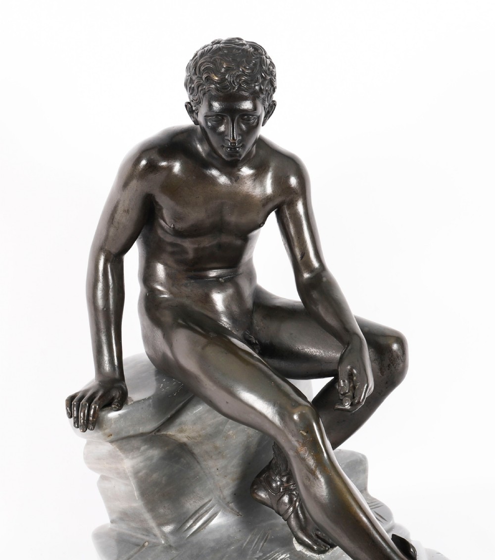 A dark patinated bronze sculpture depicting a nude seated Hermes resting on a carved grey marble base. View III