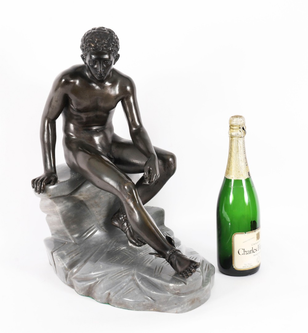 A dark patinated bronze sculpture depicting a nude seated Hermes resting on a carved grey marble base. View XX