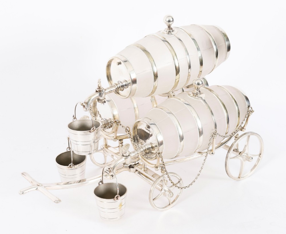 A 19th-century silver-plated carriage frame holding three frosted crystal barrels with taps and hanging miniature bucket tot cups.