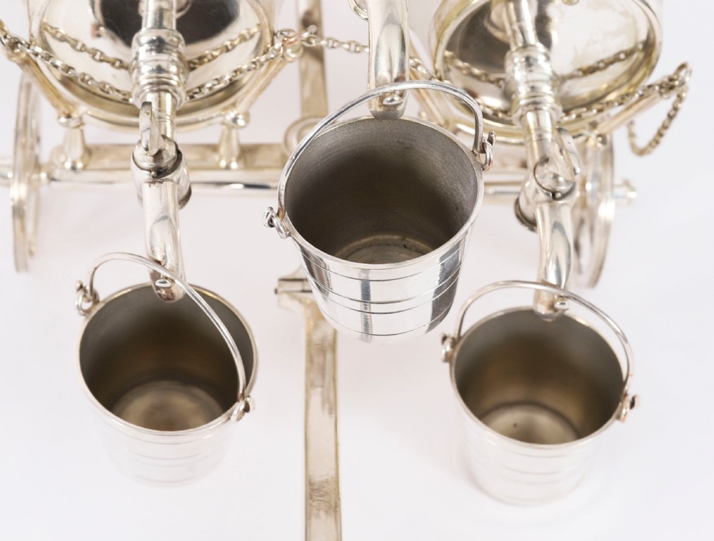 A 19th-century silver-plated carriage frame holding three frosted crystal barrels with taps and hanging miniature bucket tot cups. View IX
