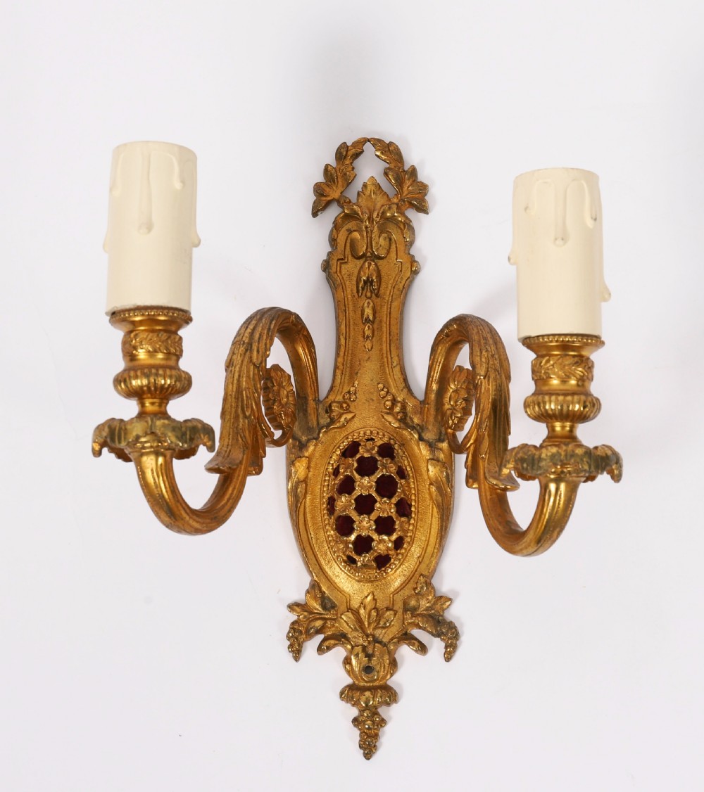 A pair of 19th-century French gilt bronze twin-light wall appliques featuring floral cresting, acanthus leaf arms, and faux candle sleeves. View II