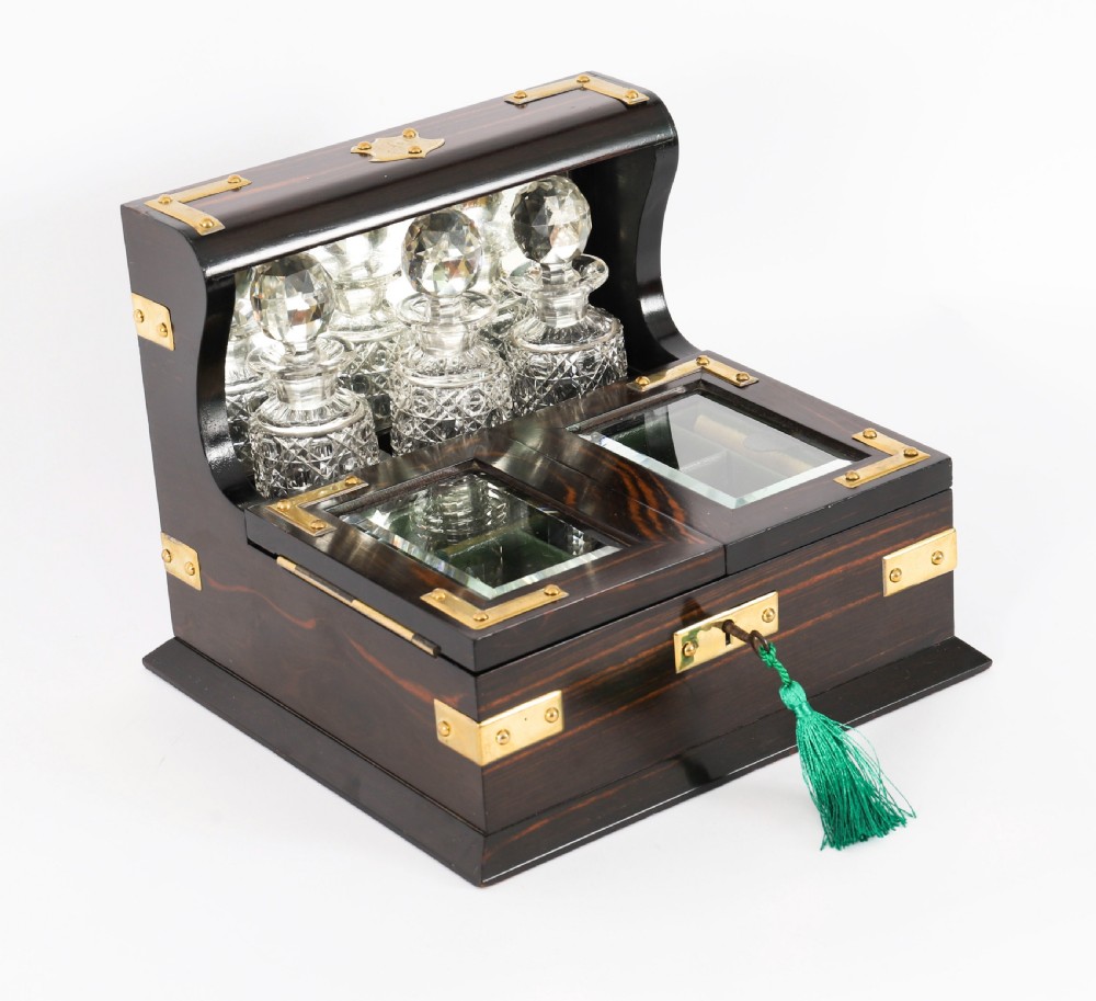 A nineteenth-century coromandel wood scent bottle casket with brass mounts opening to reveal cut-glass bottles and mirrored compartments.
