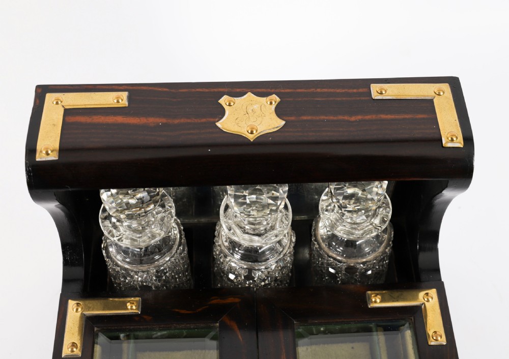 A nineteenth-century coromandel wood scent bottle casket with brass mounts opening to reveal cut-glass bottles and mirrored compartments. View III